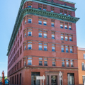 The Liberty Trust Bank (c. 1910; 81 Baltimore), one of the tallest buildings in the vicinity at seven stories, was designed by local architect Wright Butler.
