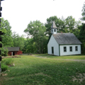 Church at right, barn at rear, cabin at left